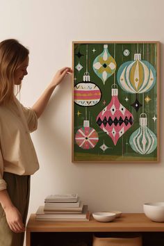 a woman standing in front of a painting on the wall next to a wooden table