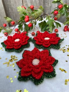 three crocheted red flowers sitting on top of a table