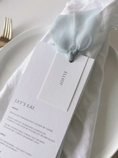 a white table setting with silverware, napkins and place settings on the plate