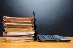 a stack of papers next to a laptop computer