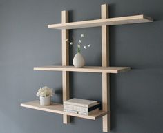 two wooden shelves with books and vases on them against a gray wall in a living room