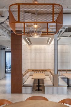 the inside of a restaurant with tables and benches in front of it, surrounded by white tiled walls