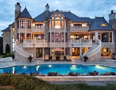 a large mansion with a swimming pool in the front yard and stairs leading up to it