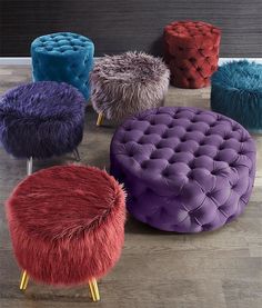 several different colored stools sitting on top of a wooden floor next to each other