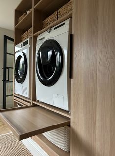 a washer and dryer in a room with wooden shelves on either side of the door