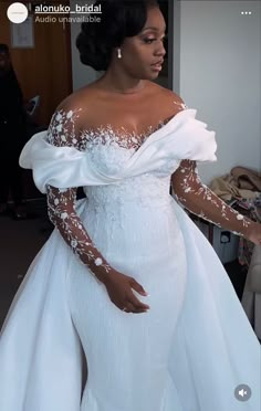 a woman in a white wedding dress standing next to a couch