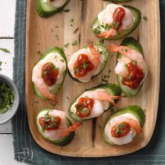 several stuffed peppers with shrimp and sauce on them, sitting on a wooden platter