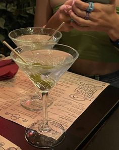 two martini glasses sitting on top of a table next to each other with sticks sticking out of them