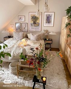 a bed room with a neatly made bed and lots of flowers on the table in front of it