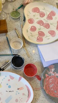 the table is covered with plates and other crafting supplies, such as paintbrushes