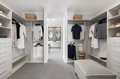 a walk in closet with white cabinets and drawers