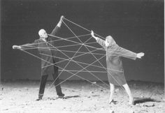 two people standing in the sand with their arms stretched out and stringing them together