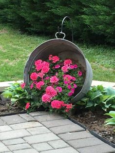 some pink flowers are in a bucket on the ground