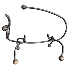 a metal object with three balls hanging from it's arms and two hands on each end