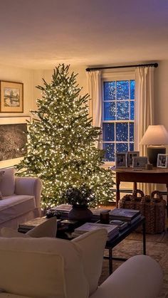 a living room filled with furniture and a lit christmas tree in the middle of it