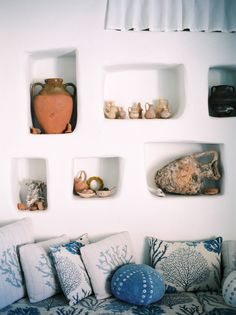 a couch with pillows and vases on the wall