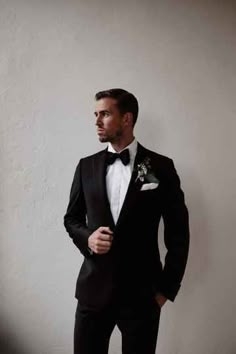 a man in a tuxedo is posing for a photo with his hands on his hips