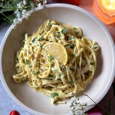 a white plate topped with pasta and lemon wedges