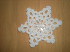 a white crocheted snowflake sitting on top of a wooden table