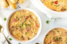 two bowls of pasta soup with bread on the side