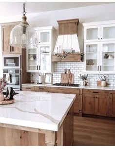 a kitchen with wooden cabinets and white marble counter tops, an island in the middle