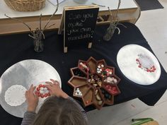 a young boy is playing with beads on paper plates