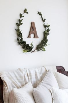 a white couch with pillows and a wreath on the wall above it that says a