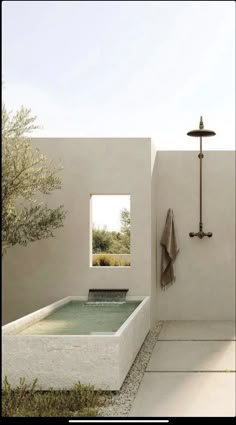 an outdoor bathtub with a shower head next to it and a towel hanging on the wall