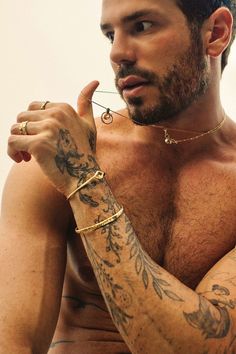 a shirtless man with tattoos on his arm and chest holding something in his hand