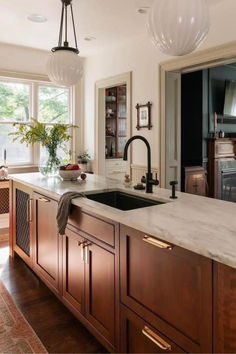 a kitchen with marble counter tops and wooden cabinets, along with an island in the middle