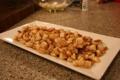 a white plate topped with tater tots on top of a counter next to a glass bowl