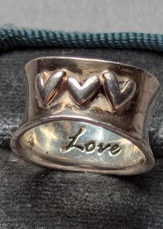 Signed LA Sterling Silver triple hearts love band ring. Ring is engraved with the word Love inside band and has three raised abstract hearts.  Ring is fully hallmarked and will arrive gift boxed. * HALLMARKS 925, LA. * SIZE 6, widest part of band measures 1/2" * CONDITION In very good to excellent condition. * MATERIALS Sterling Silver. Triple Heart, Heart Band, Love Band, Jewelry Lookbook, 925 Jewelry, Sterling Silver Heart, Engraved Rings, Ring Vintage, Ring Ring