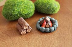 two small wooden logs sitting on top of a table next to green moss covered rocks