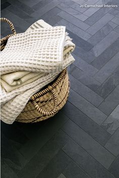 a basket filled with towels on top of a wooden floor