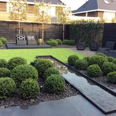 a garden with grass, rocks and water features in the foreground as well as an outdoor seating area