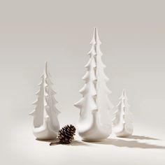 three white ceramic trees with a pine cone