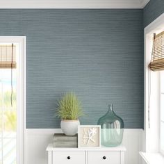 a room with blue and white walls, two vases on top of a dresser