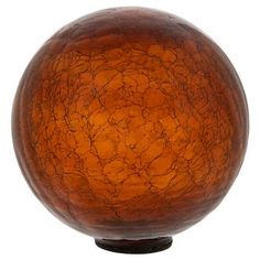 an orange glass ball sitting on top of a wooden stand