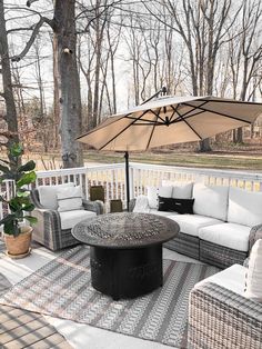 an outdoor living area with white wicker furniture and an umbrella over the couches