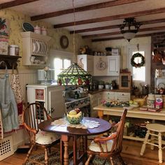 an old fashioned kitchen with wooden floors and white cabinets, including a small table in the center