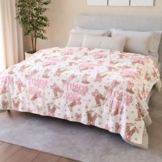 a bed with pink and white bedspread on top of it next to a potted plant