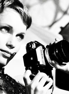 a black and white photo of a woman holding a camera