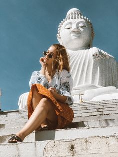 a woman sitting on top of a white buddha statue