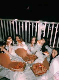 a group of girls eating pizza on a balcony