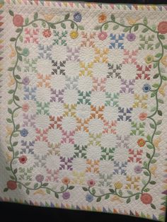 a quilt made with flowers and leaves on it's sides, in the shape of a flower