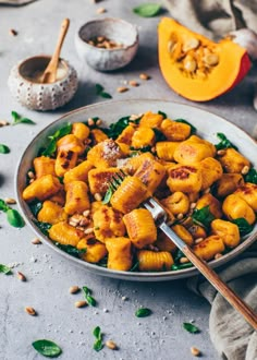 a bowl filled with pasta and spinach on top of a table