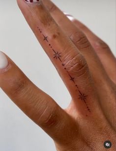 a person's hand with a small star tattoo on the middle finger and an arrow in the middle