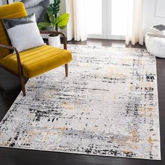 a yellow chair sitting on top of a wooden floor next to a white and black rug