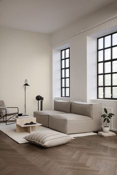 a living room with two large windows and a white couch in the middle of it