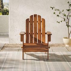 a wooden chair sitting on top of a patio next to a potted plant